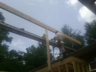 Carpenter setting a ridge beam over a new addition frame — Ice Dam Removal by Roofing Brothers in East New Market
