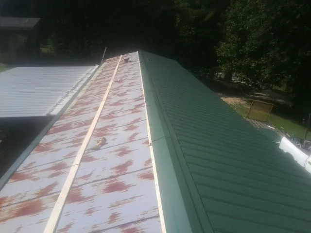 Old rusted panels beside newly installed green metal roofing — Wind Damage Roof Repair by Roofing Brothers in East New Market