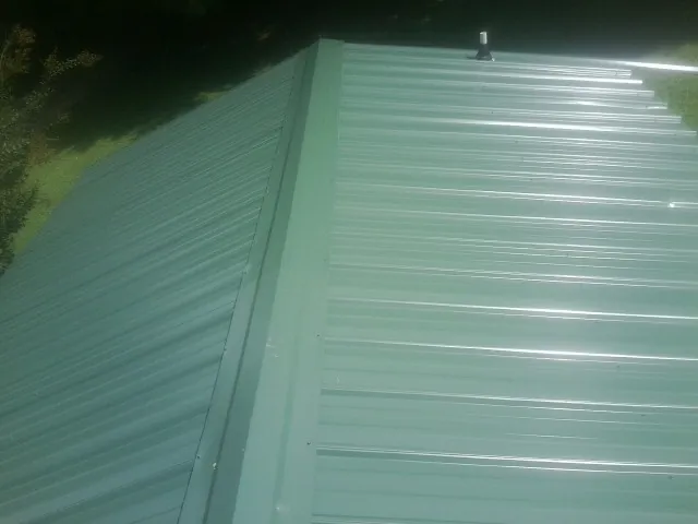 New green metal panels meeting at the ridge of a roof — Flat Roof Repair work by our crew in East New Market