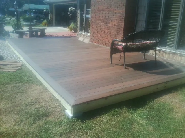 New wood deck and wicker chair beside a brick house in East New Market