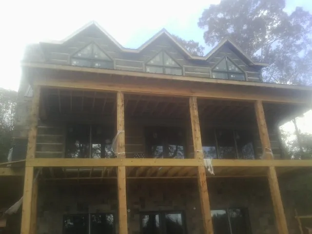 Dormers and porch framing on a large log home under construction — Roof Coating work by our crew in East New Market