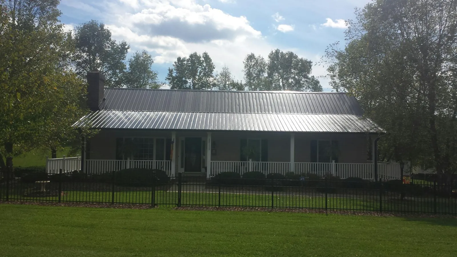 Gray metal roof on a brick ranch with a full width front porch — Gutter Guard Installation work by our crew in East New Market