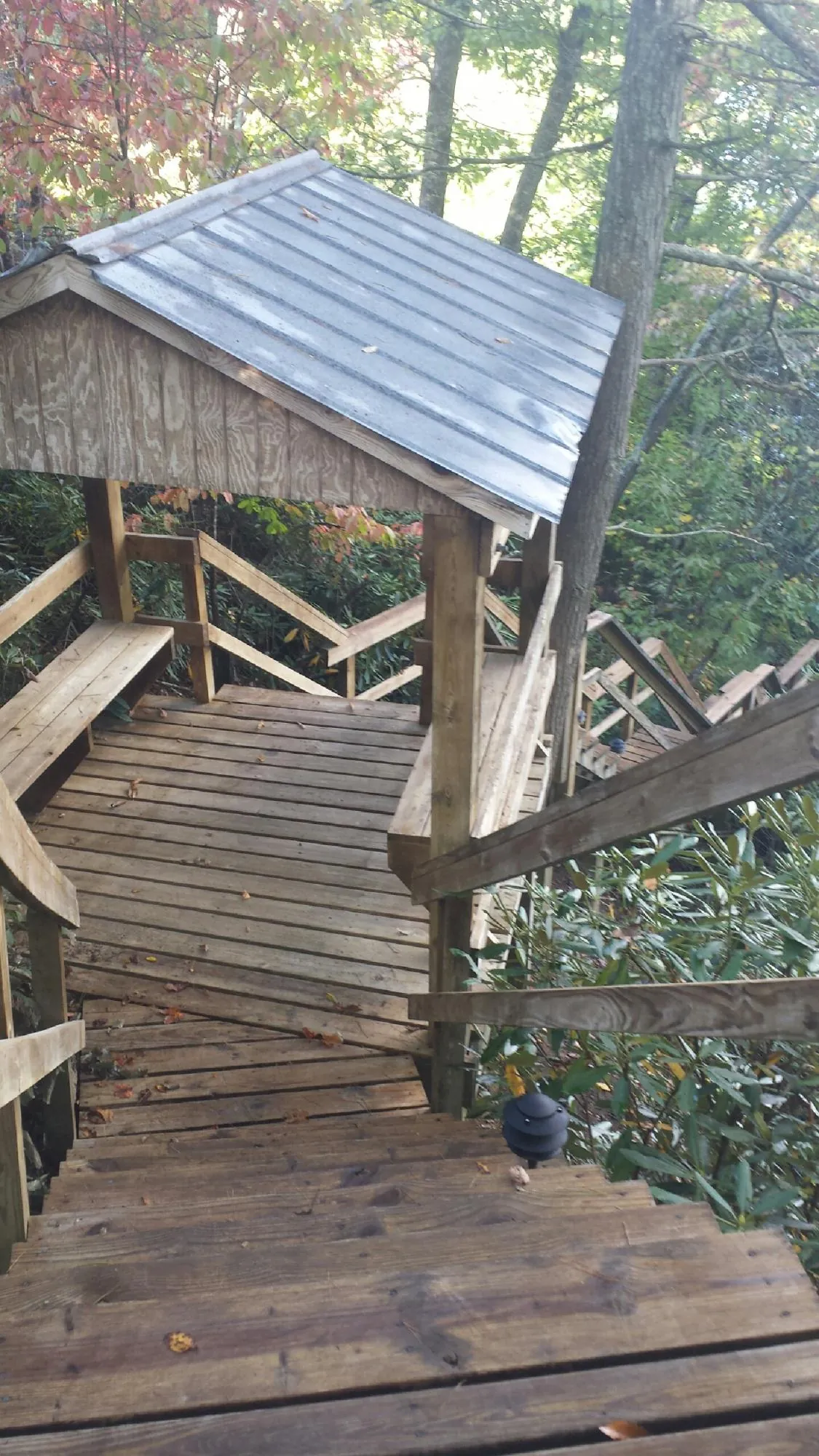 Metal roofed shelter over wooden steps on a wooded walkway — Skylight Repair & Installation work by our crew in East New Market