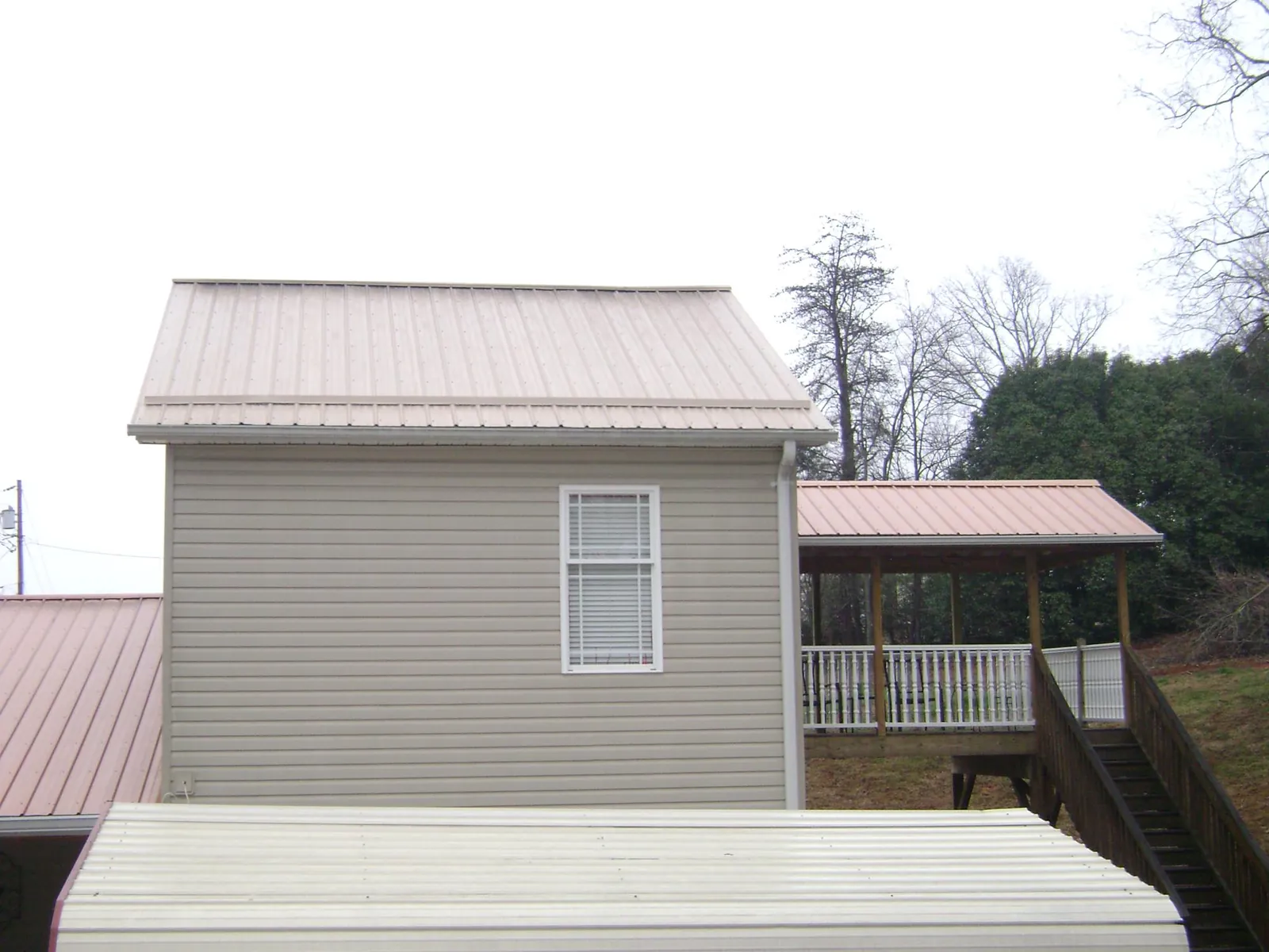 Tan metal roofs on a two story addition and attached porch, from a Roof Replacement job in East New Market